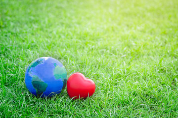 Earth with red heart on green grass, save the world, love and protect our planet, and environmental  friendly concept