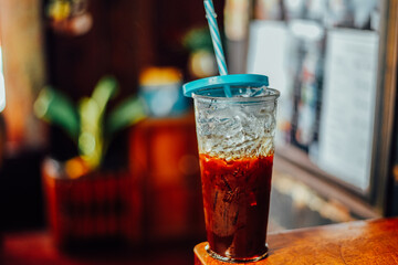 Ice coffee in a tall glass on a wood table