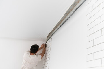 Stretch ceiling. Workers stretch the suspended ceiling in the room. Ceiling installation. - obrazy, fototapety, plakaty