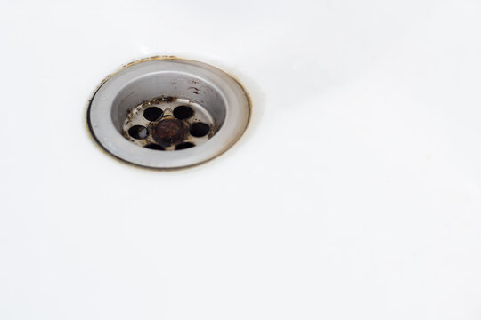 Dirty white washbasin drain in the bathroom not cleaned (rust, mold,) contaminated, dirty concept making it unhealthy. Copy space for text.