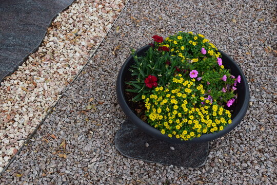 Grabschmuck aus mehrfarbigem Kies und einer Blumenschale