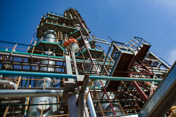 Fototapeta na wymiar Grey oil distillation towers (refining columns) and pipelines at the oil refinery plant on blue sky background. Taraz city. Kazakhstan.