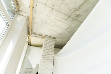 repairmen install stretch ceiling made of pvc vinyl film using a gas heat gun