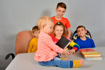 The child is sitting on the table with a serious face and with a book.