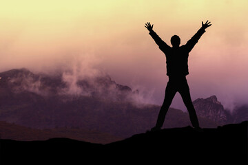 Silhouette eines Mannes mit den Armen in die Luft ausgestreckt vor imposanter Landschaft