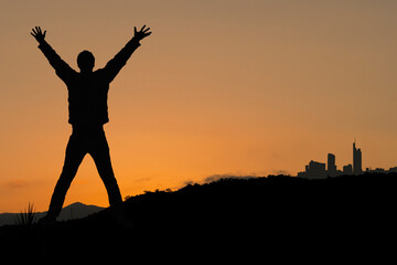 Naklejka na ściany i meble Silhouette eines Mannes mit den Armen hoch vor imposanter Landschaft