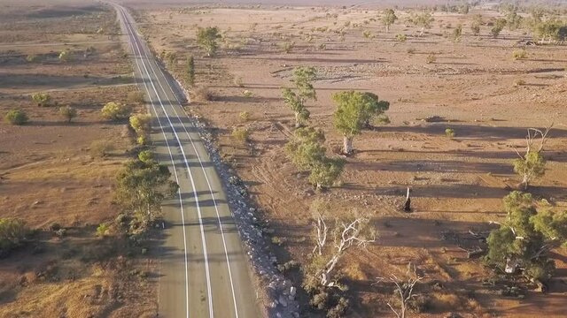 Drone lifting up over road to reveal Australian outback landscape