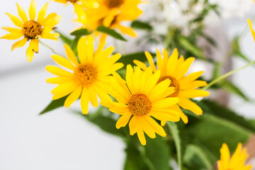bouquet of yellow flowers in a vase on a white table in the room.