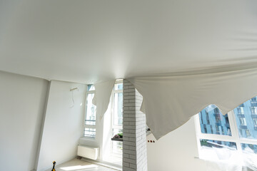 repairmen install stretch ceiling made of pvc vinyl film using a gas heat gun