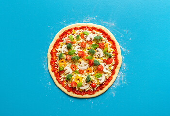 Uncooked vegetarian pizza isolated on blue background. Making pizza on a blue table, above view