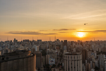 Por do Sol da cidade de São Paulo mostrando o centro histórico com seus prédios e helicóptero no céu