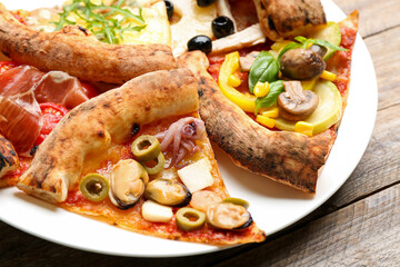 Slices of different pizzas on wooden table, closeup