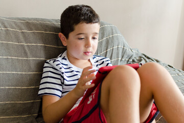 Niño sentado en el sofá mientras utiliza su tableta