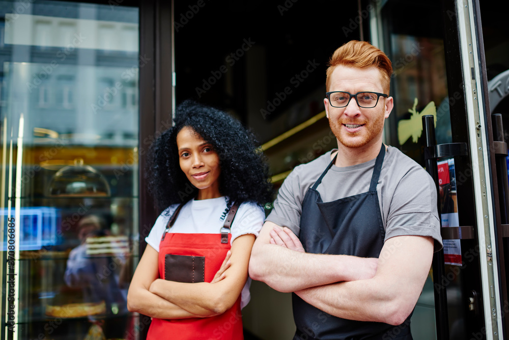 Poster portrait of prosperous team of two multicultural professional barista and waitress with crossed hand
