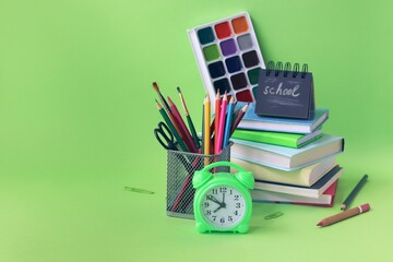 Back to school, stationery, books, alarm clock on bright background, home learning concept, part of children's interior