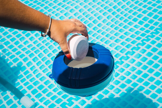 Woman's Hands Pouring Chlorine Into The Pool