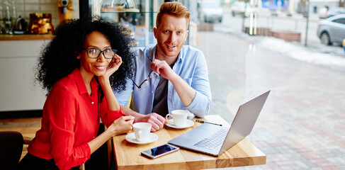 Cheerful multiracial business partners having work meeting in cozy coffee shop