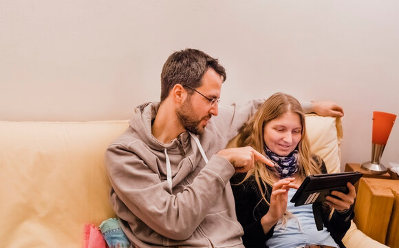 Couple Using Digital Tablet On Sofa