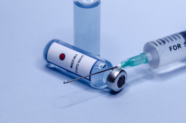 Coronavirus vaccine in glass vials with a syringe on a blue background.