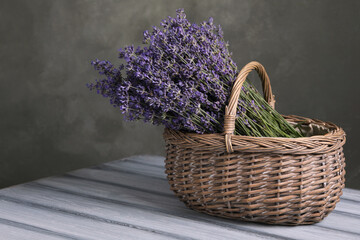 Fototapeta premium Beautiful fresh lavender flowers in wicker basket on wooden table against grey background