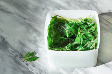 Frozen mint or Melissa. Storage of frozen food. Frozen product. Frozen green leaves of Melissa or mint in a container.