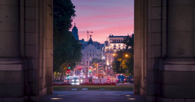 Time lapse during sunset of Metropolis building and Cibeles seen through Puerta de Alcala monument in Madrid, Spain.