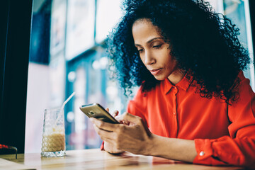 Pensive african american young woman chatting online on smartphone device using free 4G internet...
