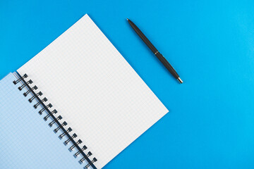 Checkered notebook with a black pen on a blue background. Place for text.