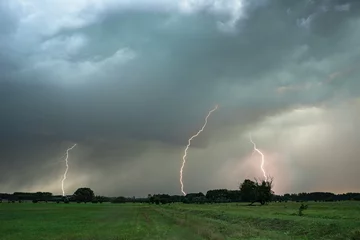 Fototapeten Several lightning bolts strike down from a severe thunderstorm in Hungary © Menyhert