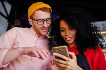 Happy waitress showing phone to friend
