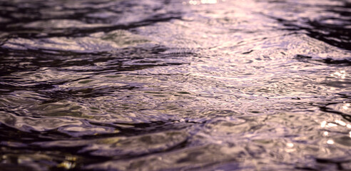 Violet reflections on the water surface, movements of light on the waves. Perfect background image. Beautiful pattern