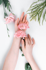 Elegant female hands hold a rosebud eustoma in the palm. White background. Flat lay. The concept of Floristics and tenderness