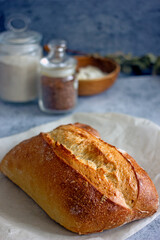 Homemade sourdough bread on a dark table with a napkin, next to flour. Loaf of freshly baked bread close up, vertical background