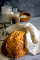 Homemade sourdough bread on a dark table with a napkin, next to flour. Loaf of freshly baked bread close up, vertical background