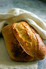Homemade sourdough bread on a dark table with a napkin, next to flour. Loaf of freshly baked bread close up, vertical background