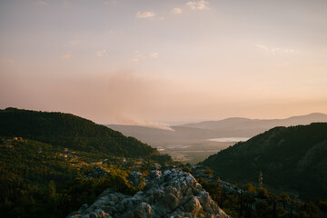 Fototapeta na wymiar A column of smoke on the Lustica Peninsula in Montenegro. Wildfires rage at sunset.