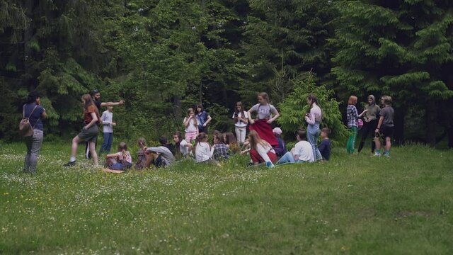 Teens sitting on mats in forest.