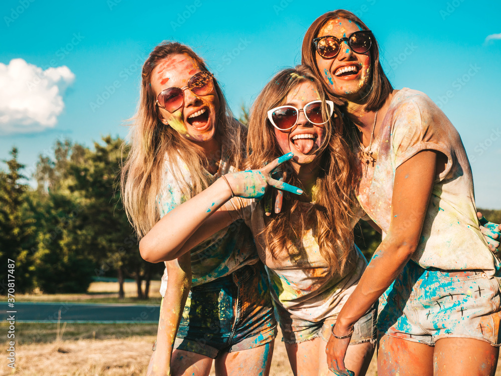 Wall mural three happy beautiful girls making party at holi colors festival in summer time.young smiling women 