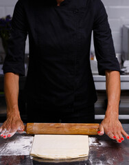 The chef prepares pastries in a professional kitchen. Dark background.