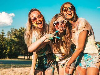Three happy beautiful girls making party at Holi colors festival in summer time.Young smiling women...