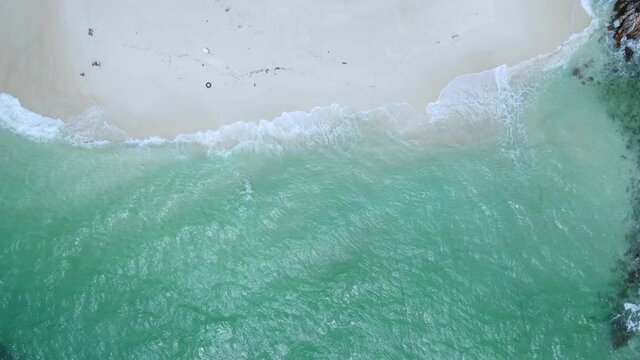 Drone view of beautiful seamless never ending footage while turquiose sea waves breaking on sandy coastline. Aerial shot of golden beach meeting deep blue ocean water and foamy waves phuket Thailand.