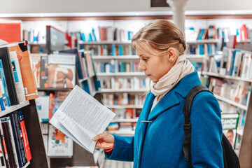 A woman leafing through a book in a store. Side view. The concept of buying books and preparing for school