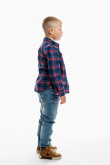 The boy is standing. A cute fat schoolboy in jeans, a shirt and a white T-shirt. Full height. White background. Vertical. Side view.