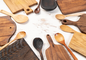 Set of various kitchen utensils - wood cutting boards, spoons and fork on rustic white wooden background.