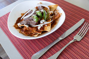 Traditional mexican breakfast chilaquiles served on the table