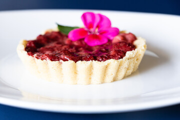 Close up of small raspberry tart with flower