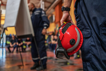 Closeup of firefighter holding a helmet and listening to his boss who is drawing and talking about...