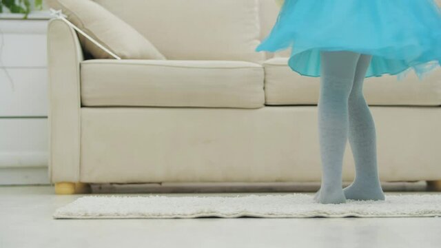 Cropped legs of little girl in blue skirt dancing around with her best friend Teddy Bear.