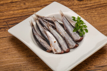 Anchovies in the bowl served basil leaves