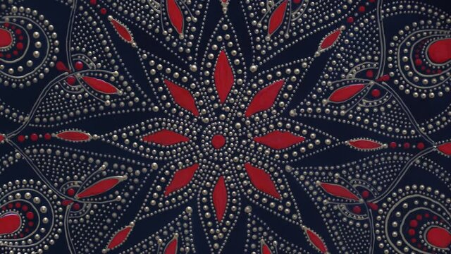 Decorative ceramic plate with black, red and golden colors, painted plate on background, closeup, top view, rotate. Decorative porcelain plate painted with acrylic paints, handwork, dot painting